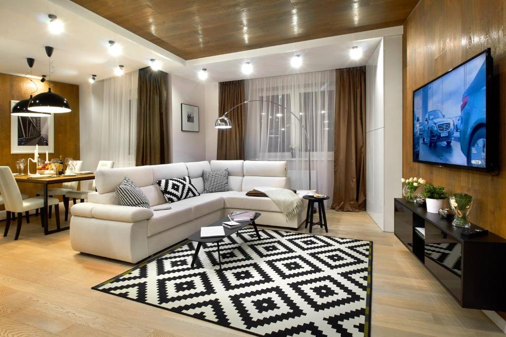 a living room with a white couch and a tv at EXCLUSIVE EuApartments in Grodno