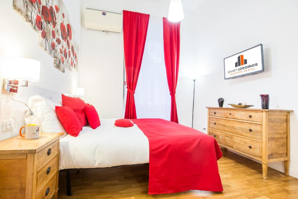 a bedroom with red curtains and a bed and a dresser at Smart Lodgings Plus in Rome