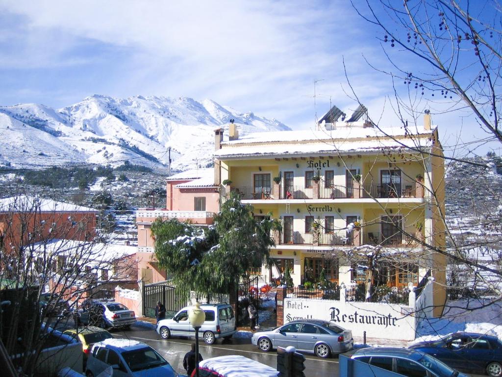 un edificio en una calle de la ciudad con montañas cubiertas de nieve en Hotel Rural Serrella en Castell de Castells