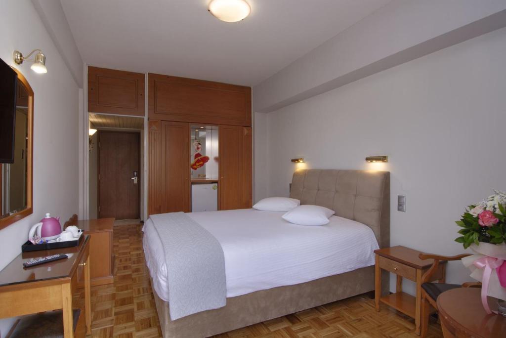 a bedroom with a white bed and a desk and a room at Hotel Nefeli in Volos
