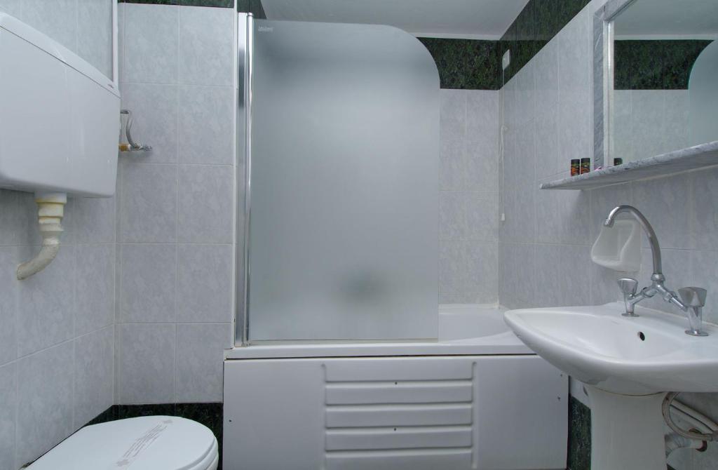 a white bathroom with a sink and a toilet at Hotel Nefeli in Volos
