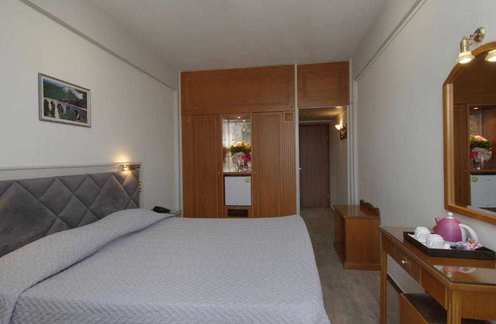 a bedroom with a bed and a table and a drawer at Hotel Nefeli in Volos