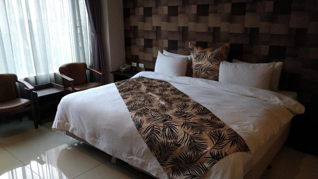 ein Schlafzimmer mit einem großen weißen Bett mit einer Decke darauf in der Unterkunft Boston Plus Hotel in Chiayi