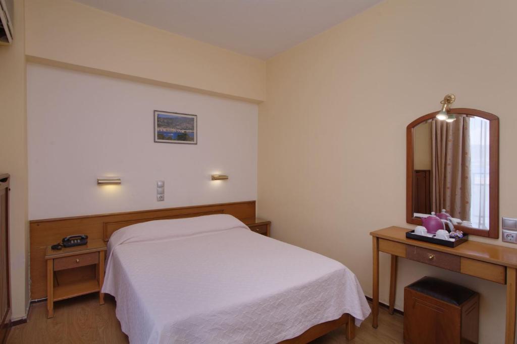 a bedroom with a white bed and a mirror at Hotel Nefeli in Volos