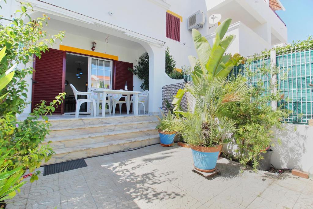 une maison avec une terrasse couverte dotée d'une table et de plantes en pot dans l'établissement Prestige for Home - Apt Dunamar - Praia Alagoa Altura, à Altura