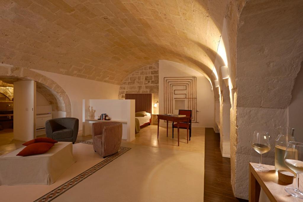 una sala de estar con una cama y una habitación con una mesa. en Fra I Sassi Residence, en Matera