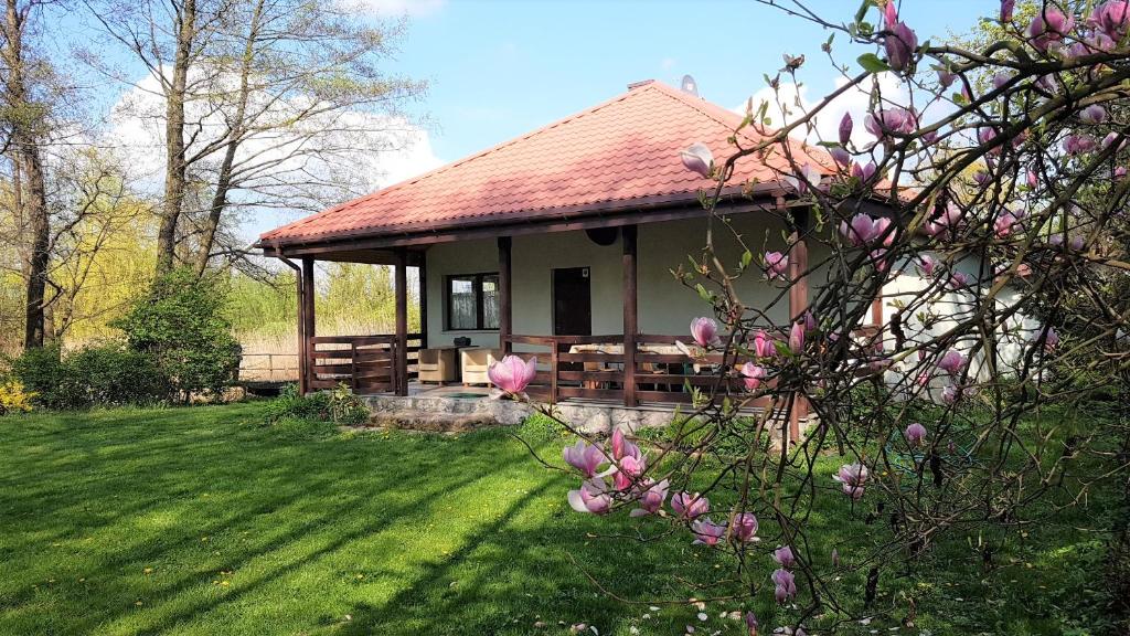 ein Gebäude mit einem Picknicktisch und einem Baum mit rosa Blumen in der Unterkunft Domek w NABO in Załuski