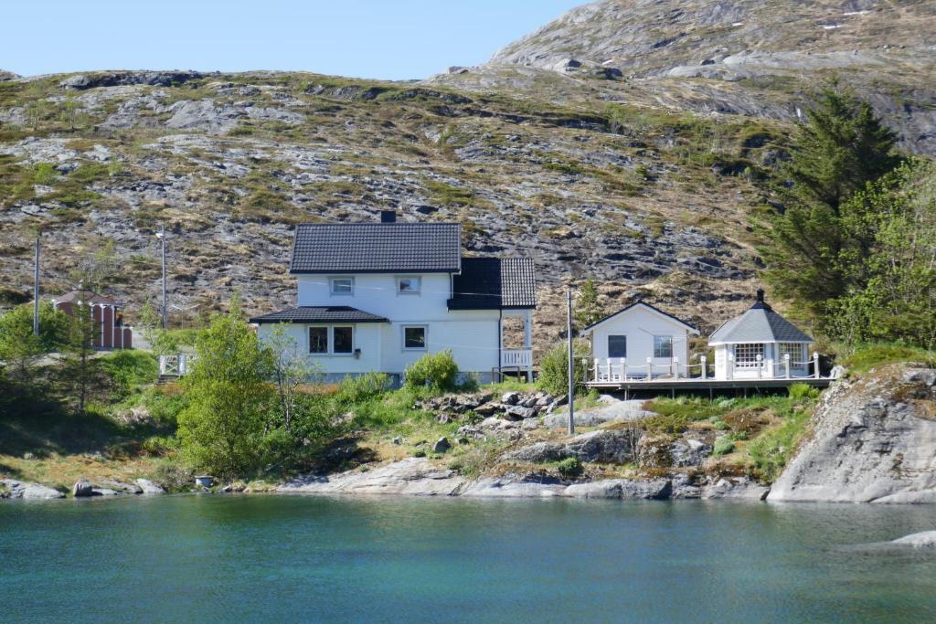 una casa en una colina junto a un cuerpo de agua en Seafront Holiday Home close to Reine, Lofoten en Sund