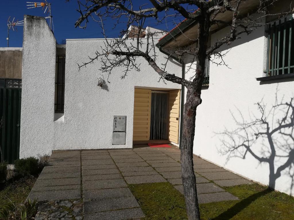 un edificio bianco con una porta e un albero di Refúgio do Douro Guest House a Bemposta