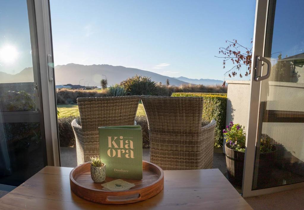 een boek op een tafel voor een raam bij Dunluce Boutique B&B in Te Anau