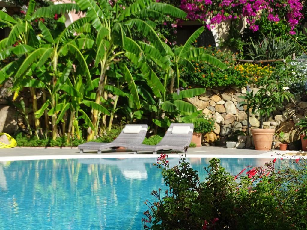 a swimming pool with two lounge chairs and flowers at Hotel Mariposas in Villasimius