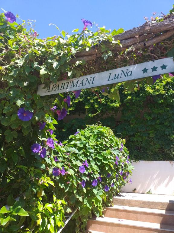 una señal para un jardín con flores púrpuras en Apartmani LuNa, en Hvar