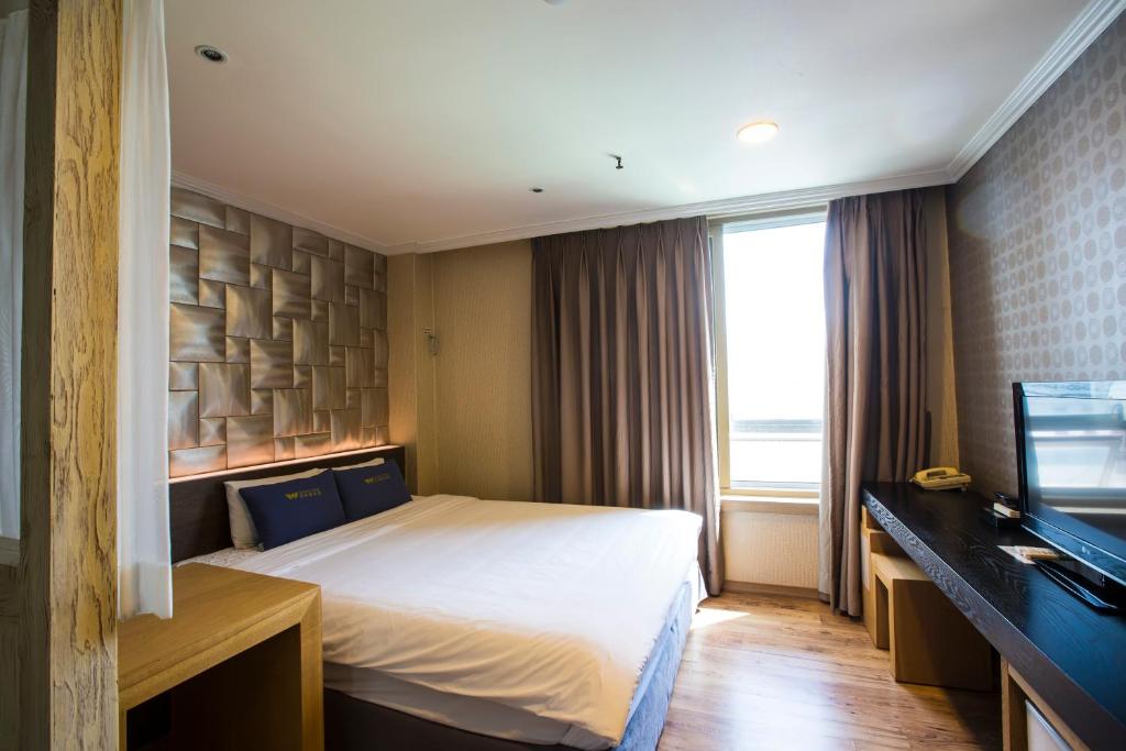 um quarto de hotel com uma cama e uma televisão em Central Hotel em Changwon
