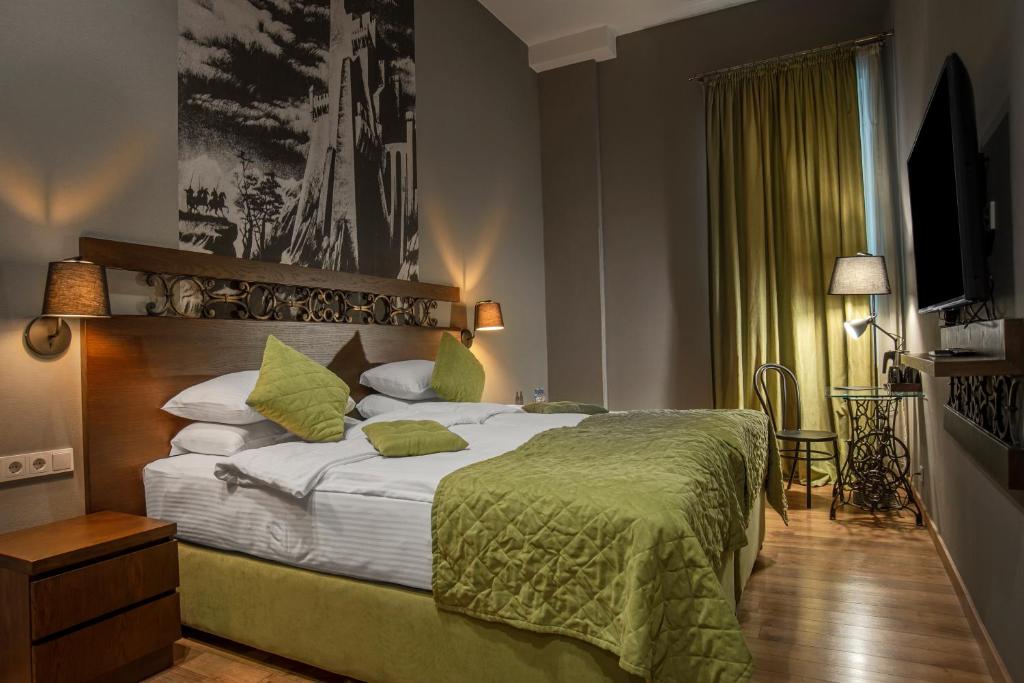 a bedroom with a bed, a lamp, and a painting on the wall at Badagoni Boutique Hotel Rustaveli in Tbilisi City