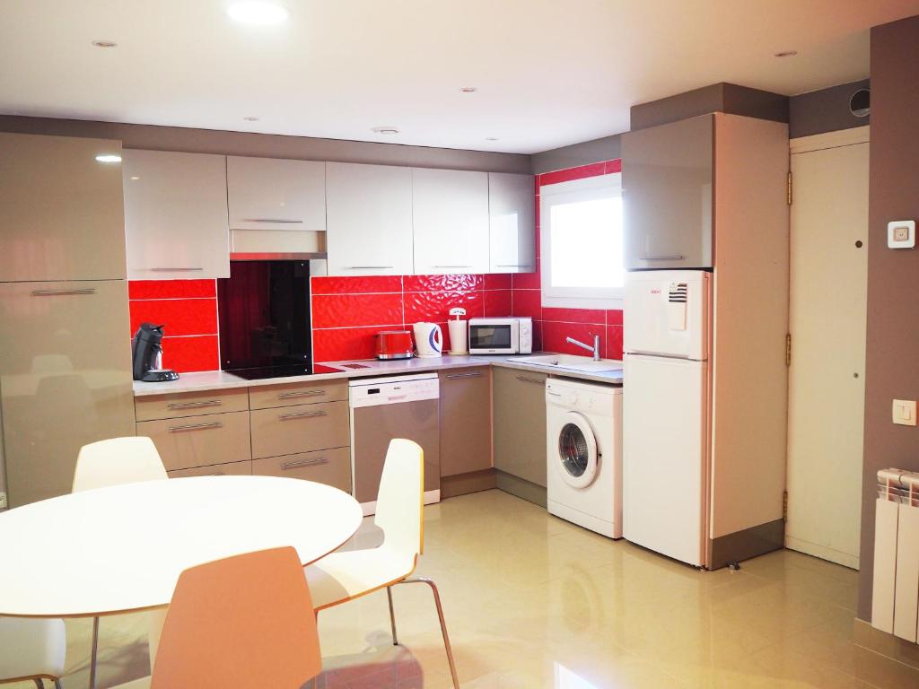 a kitchen with red walls and a table with chairs at Apartament per 4 persones a Doctor Fleming a 5 minuts de la Platja Gran in Platja  d'Aro