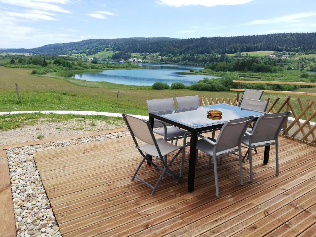 una mesa y sillas en una terraza con vistas al lago en L'esca'Lac en Grande Riviere