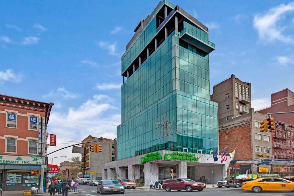 ein hohes Glasgebäude in einer Stadtstraße mit Autos in der Unterkunft Wyndham Garden Chinatown in New York