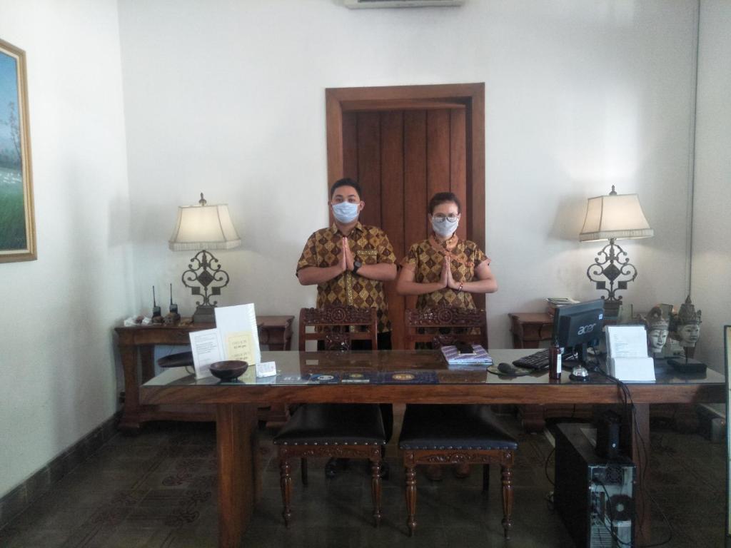 Hotel Graha Kinasih Kotabaru في يوغياكارتا: شخصان يقفان على طاولة يلبسان اقنعة