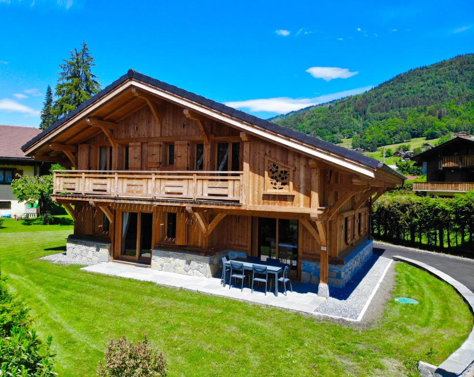 uma grande casa de madeira com um relvado verde em Chalet luxe L'HIBISCUS em Samoëns
