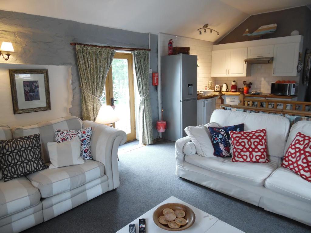 a living room with two white couches and a kitchen at Brambles Cottage in Boyton