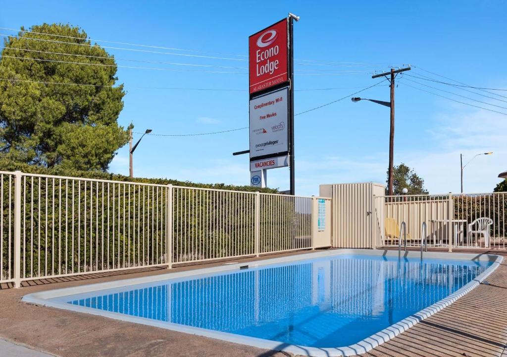 a swimming pool with a sign in front of a fence at Econo Lodge Alabaster in Cowra
