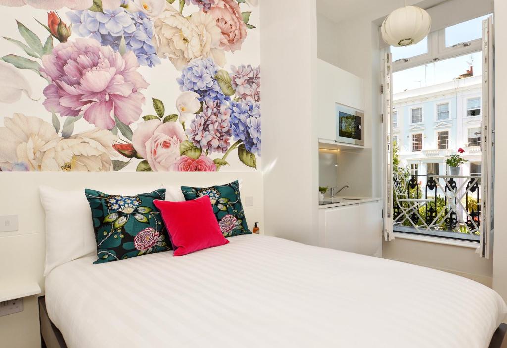 een slaapkamer met een wit bed met bloemen aan de muur bij The Portobello Serviced Apartments by StayPrime in Londen
