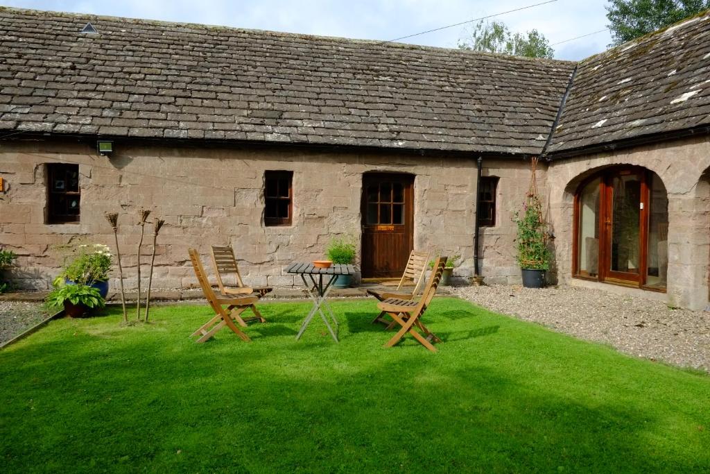 un jardín con sillas y una mesa frente a un edificio en Farmtoun Cottage Apartment en Forfar