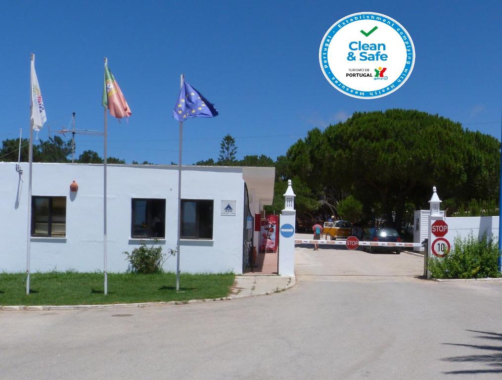 Un bâtiment blanc avec des drapeaux devant lui dans l'établissement Parque de Campismo Orbitur Sagres, à Sagres