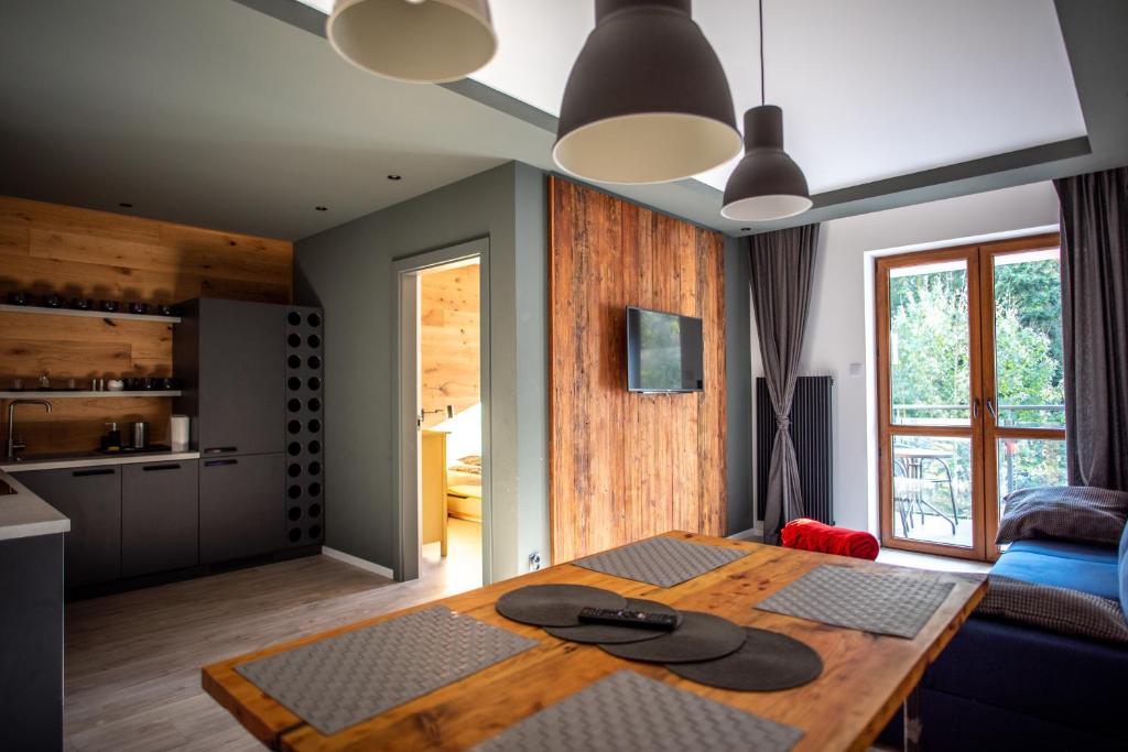 een woonkamer met een houten tafel en een keuken bij Apartament ZIELONA in Krynica Zdrój