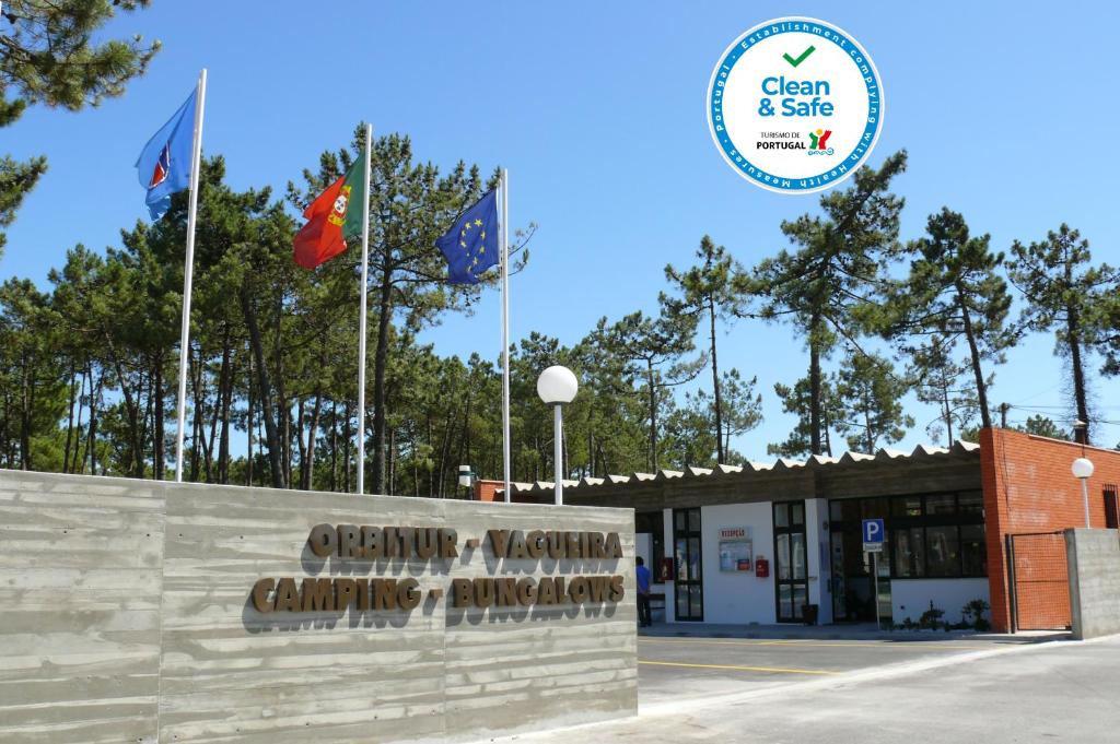 a sign in front of a building with flags at Parque de Campismo Orbitur Vagueira in Gafanha da Boa Hora