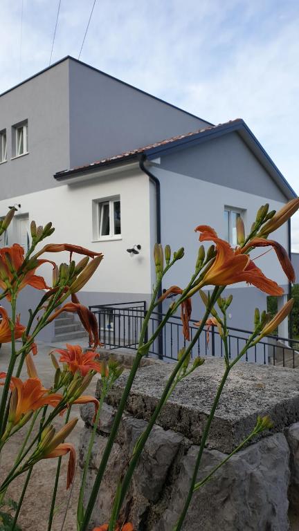 ein weißes Haus mit orangefarbenen Blumen davor in der Unterkunft Villa Zita Lovran in Opric