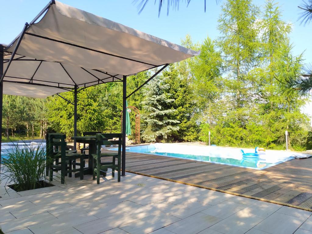 una mesa y sillas bajo una sombrilla junto a la piscina en Dom z basenem nad Narwia, en Szablak