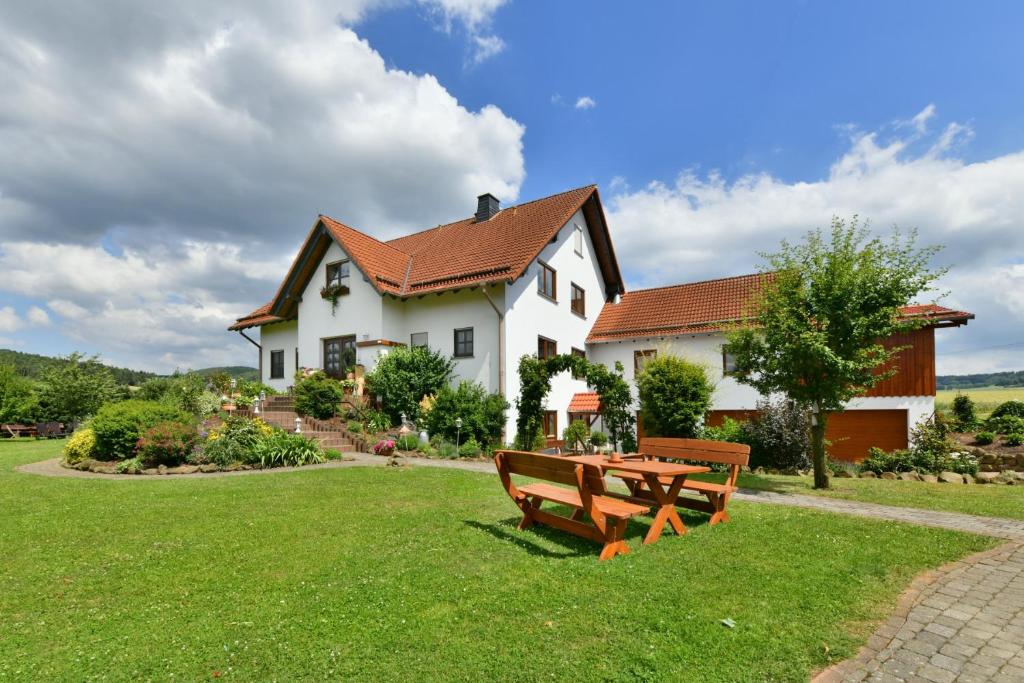 una casa con un banco de picnic delante de ella en Oberlützenbachshof, en Geisa