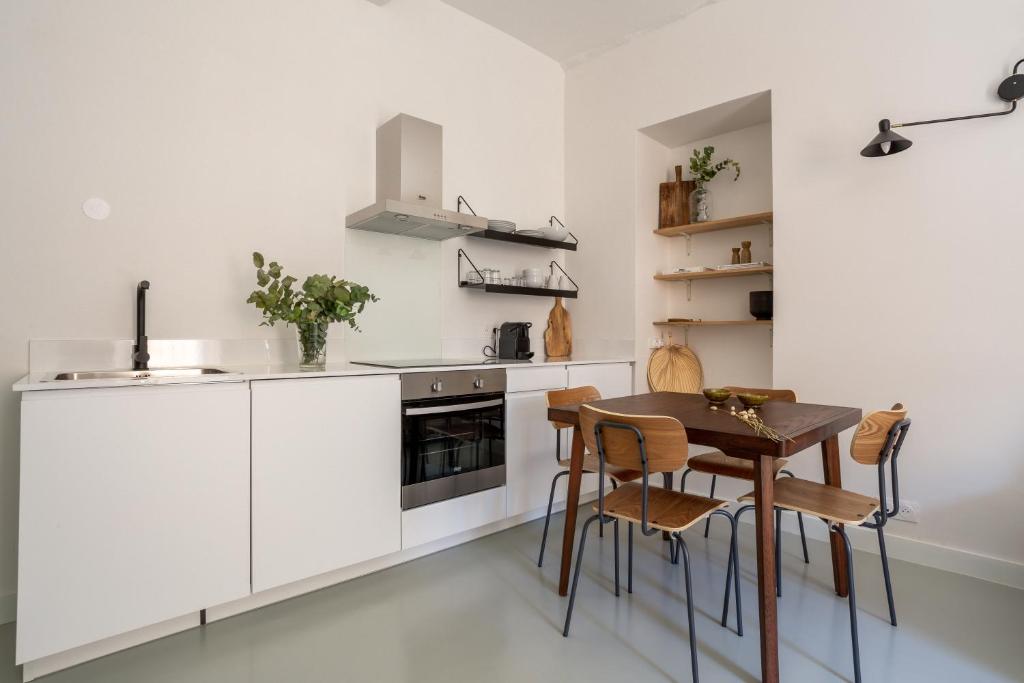 une cuisine avec des armoires blanches et une table et des chaises dans l'établissement Plage à pied au cœur du vieil Antibes, à Antibes