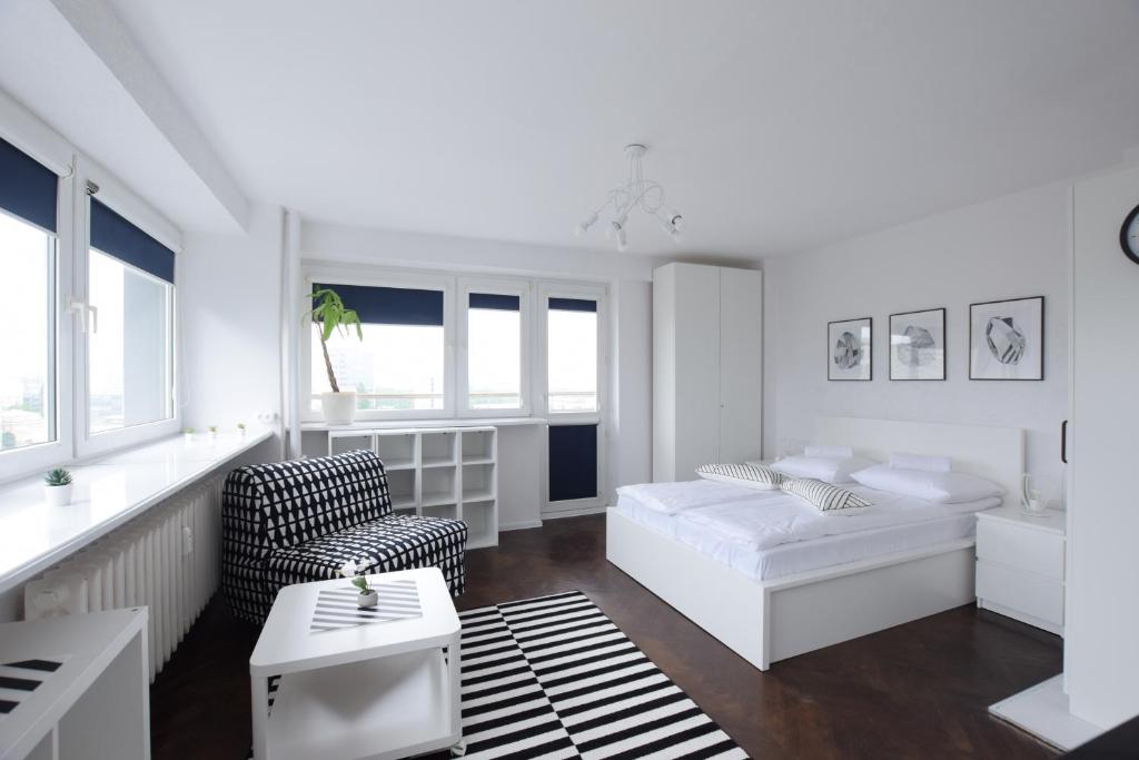 Biały salon z łóżkiem i krzesłem w obiekcie Elegant Apartment Warsaw View w Warszawie