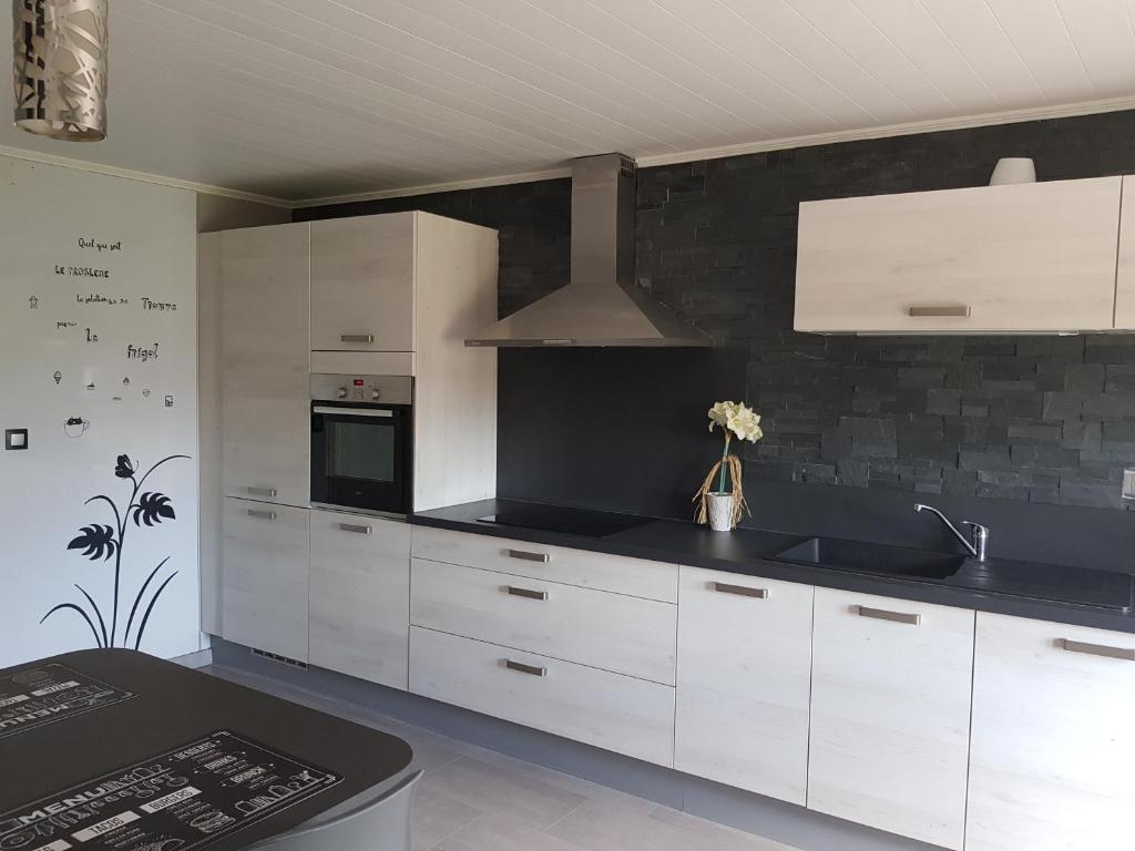 une cuisine avec des placards blancs et un mur noir dans l'établissement gite de plaisance, à Lagarde