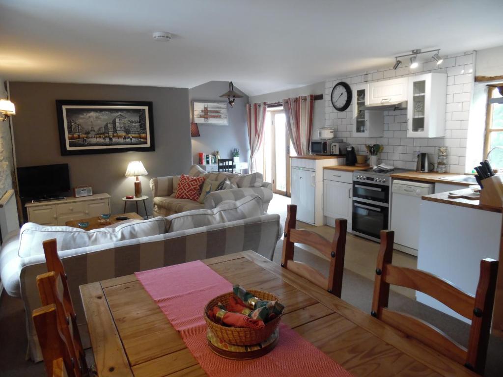 eine Küche und ein Wohnzimmer mit einem Sofa und einem Tisch in der Unterkunft Primrose Cottage in North Petherwin