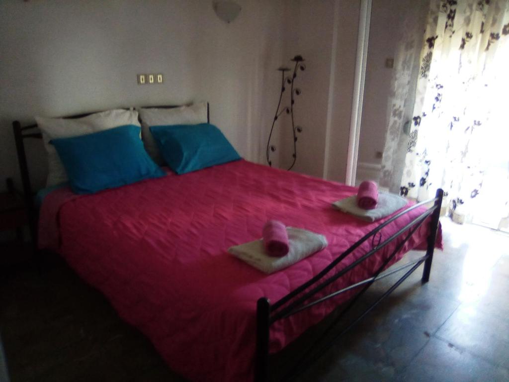 1 Schlafzimmer mit einem Bett mit rosa Bettwäsche und 2 Handtüchern in der Unterkunft Nikos Rooms in Loutra Edipsou