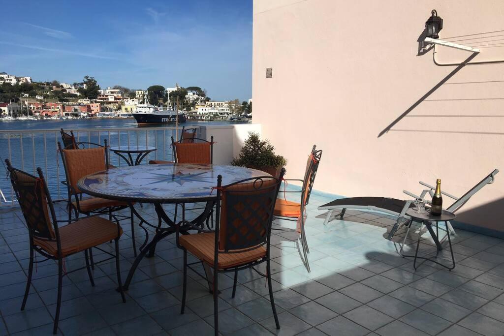 una mesa y sillas en un patio con vistas al agua en Panorama da Cartolina, en Isquia