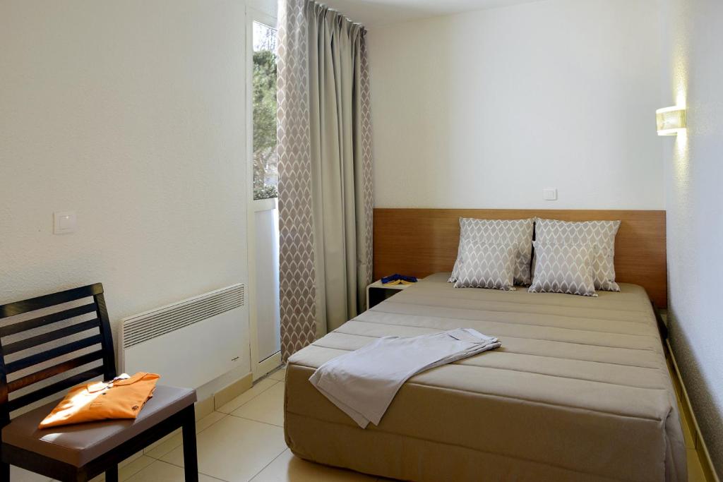 um quarto com uma cama, uma cadeira e uma janela em Residence Residéal La Grande Motte em La Grande-Motte