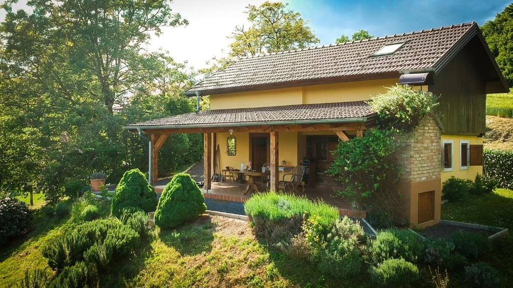 une petite maison jaune avec une terrasse dans une cour dans l'établissement Green Hills Cottage in Zagorje with magnificent view, à Ravnice-Desinićke