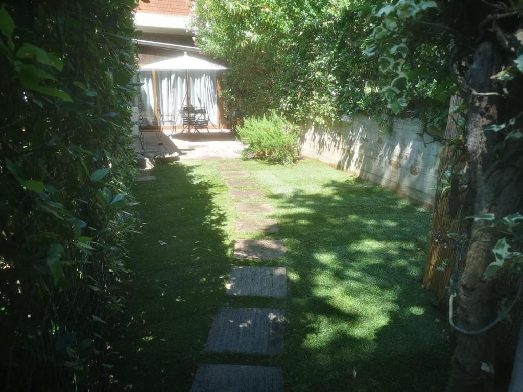 einen Garten mit einem Weg, der zu einem Haus führt in der Unterkunft Ala Garden Apartment in Punta Ala