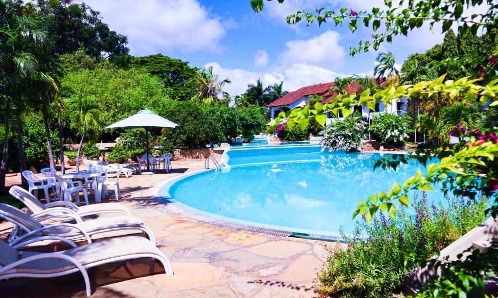 uma piscina num resort com cadeiras e mesas em Woburn Residence Club Apartments em Melinde