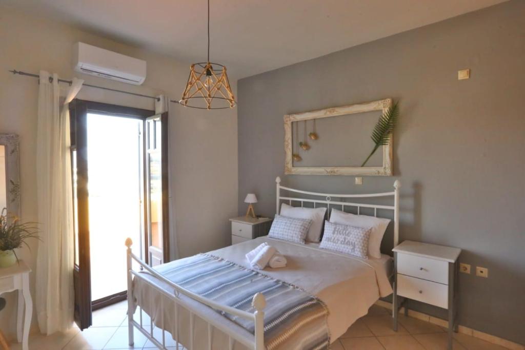 1 dormitorio con cama con espejo y ventana en Aegean Emerald, en Azolimnos