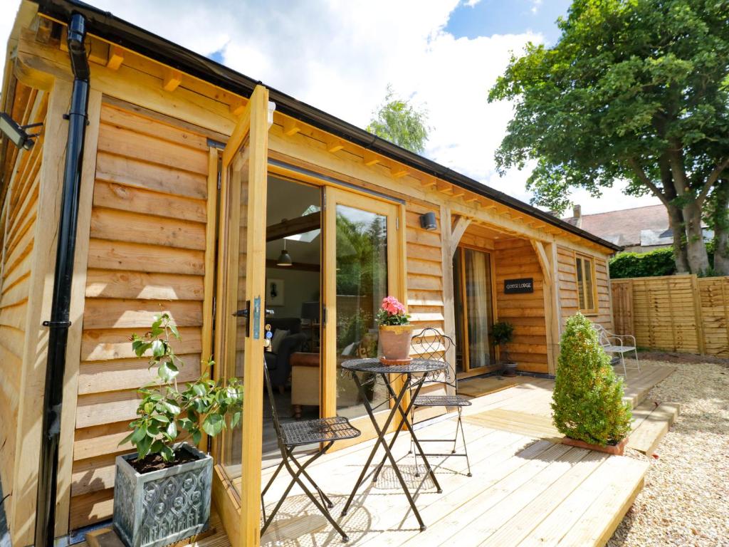 a wooden cabin with a patio and a table at Goose Lodge in Shipston-on-Stour