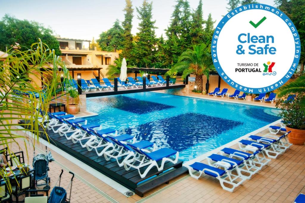 una piscina con sillas y un cartel que diga limpio y seguro en Hotel Balaia Mar, en Albufeira