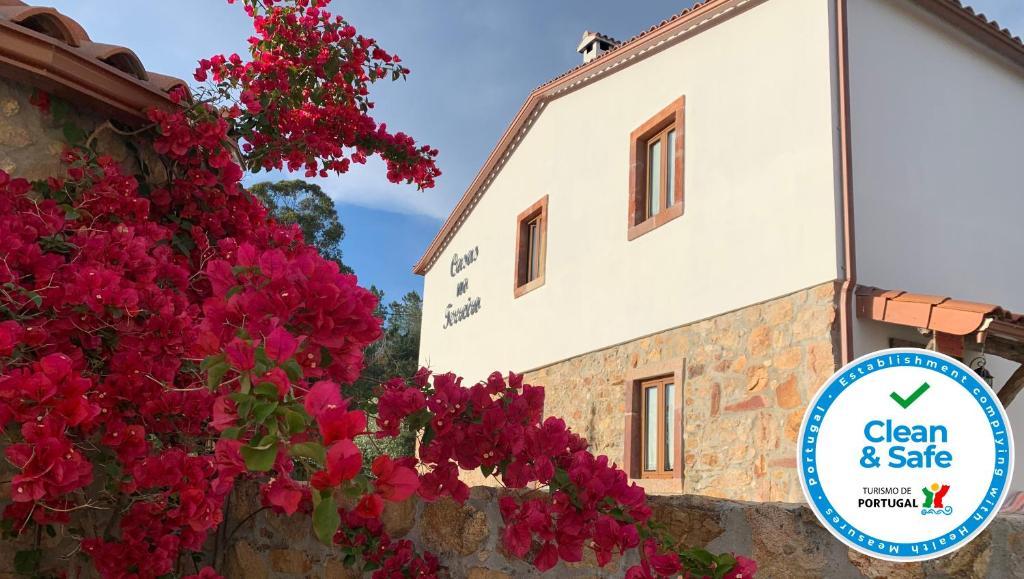 a building with pink flowers next to a wall with a sign at Casas no Terreiro in Penacova