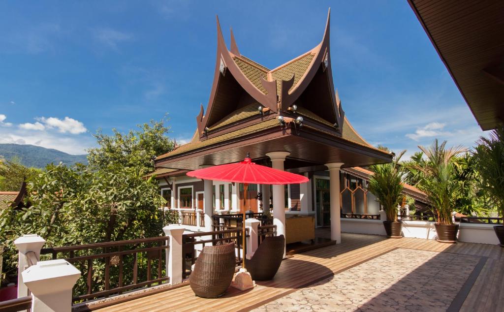 a house with a red umbrella on a deck at Sireeampan Boutique Resort and Spa - SHA Extra Plus in Chiang Mai