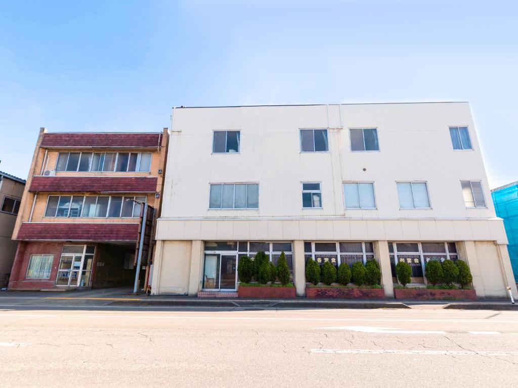 a white building on the side of a street at Tabist Business Hotel Chitose Kashiwazaki in Kashiwazaki