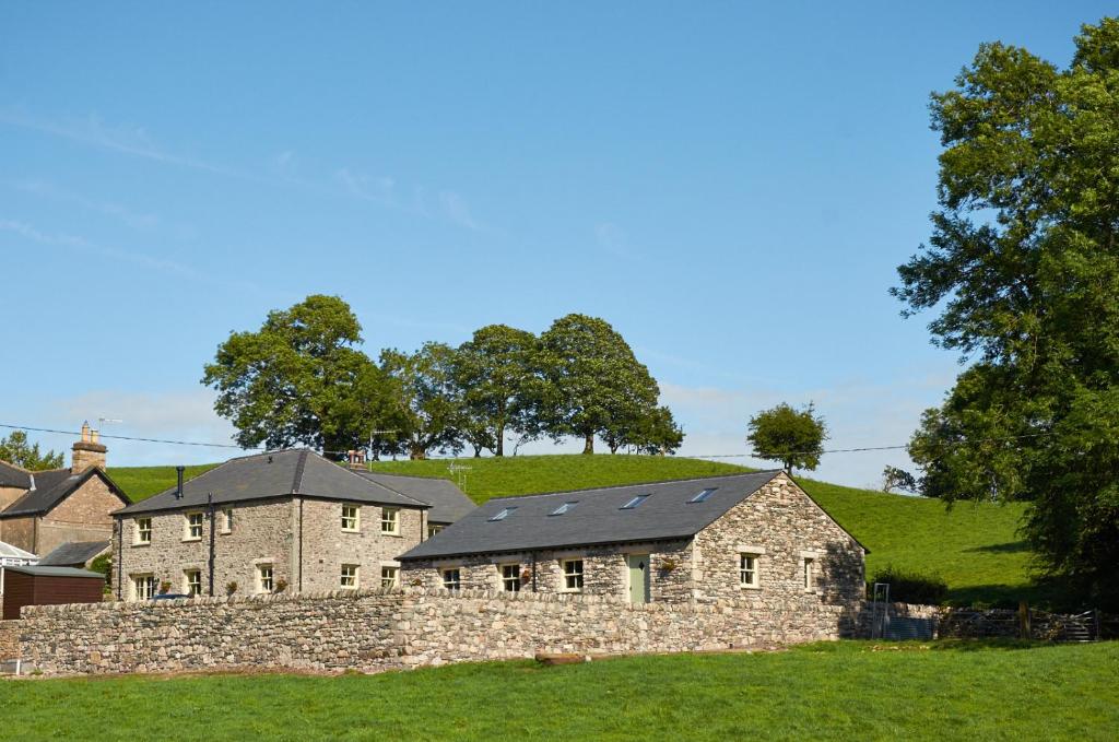 una gran casa de piedra con una pared de piedra en Helm Mount Lodge & Cottages, en Kendal